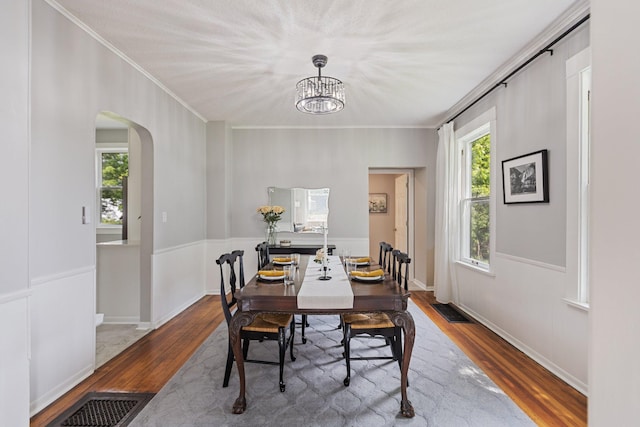 810 7th St NW, Faribault, MN 55021 - dining room featuring wood finished floors, crown molding, arched walkways, and a chandelier