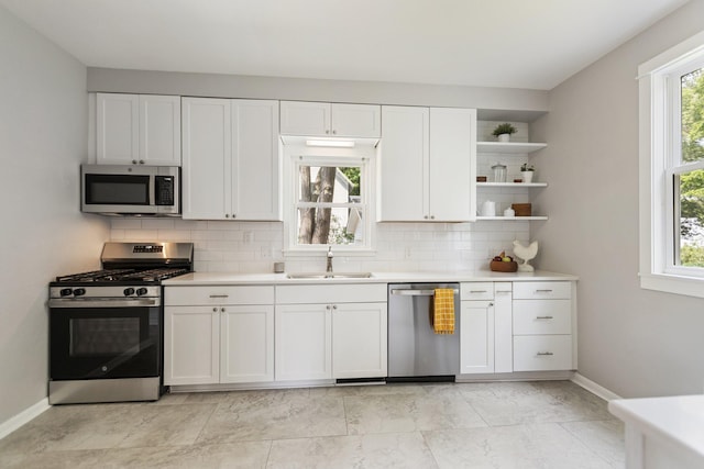 810 7th St NW, Faribault, MN 55021 - kitchen featuring appliances with stainless steel finishes, decorative backsplash, light countertops, white cabinetry, and open shelves