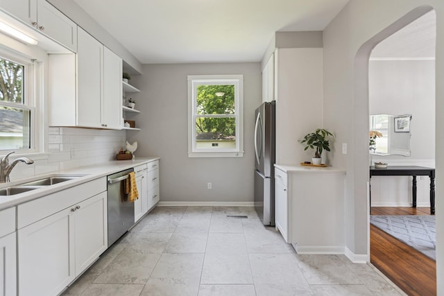 810 7th St NW, Faribault, MN 55021 - kitchen featuring stainless steel appliances, arched walkways, white cabinets, open shelves, and backsplash
