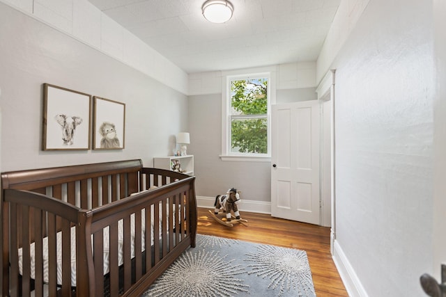 810 7th St NW, Faribault, MN 55021 - bedroom featuring wood finished floors and a nursery area