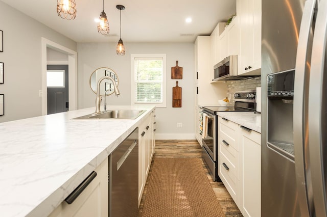 202 Park St, Alexandria, MN 56308 - kitchen with appliances with stainless steel finishes, dark wood-style floors, white cabinetry, decorative light fixtures, and tasteful backsplash