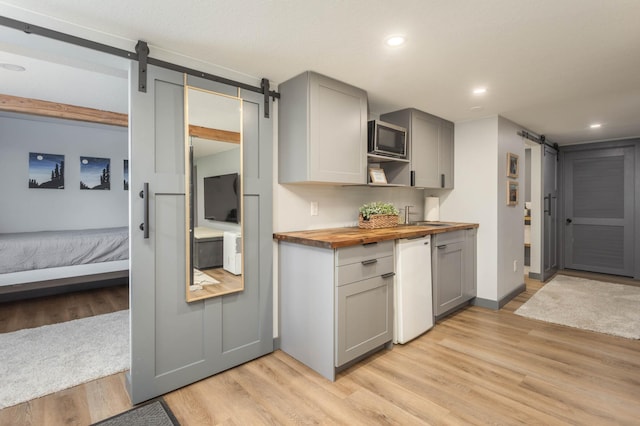 202 Park St, Alexandria, MN 56308 - kitchen featuring a barn door, butcher block counters, gray cabinets, light wood-style flooring, and recessed lighting