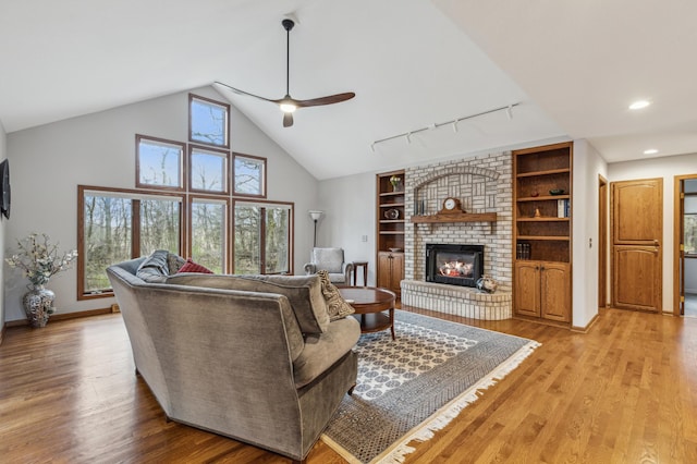 8011 County Road 13 SE, Delano, MN 55328 - living room featuring a ceiling fan, a fireplace, light wood-type flooring, rail lighting, and vaulted ceiling