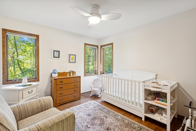 8011 County Road 13 SE, Delano, MN 55328 - bedroom featuring a crib, wood finished floors, and ceiling fan