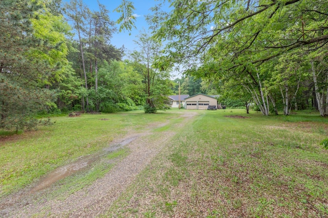 13143 County Road 116, Center Twp, MN 56465 - view of green lawn featuring dirt driveway, a garage, and a forest view