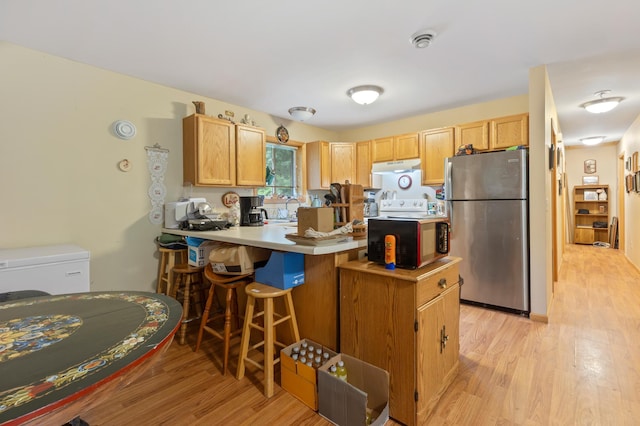 13143 County Road 116, Center Twp, MN 56465 - kitchen featuring freestanding refrigerator, under cabinet range hood, a peninsula, light wood-type flooring, and a kitchen breakfast bar