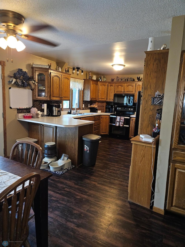 147 5th St, Felton, MN 56536 - kitchen featuring black appliances, brown cabinets, a peninsula, a textured ceiling, and dark wood finished floors