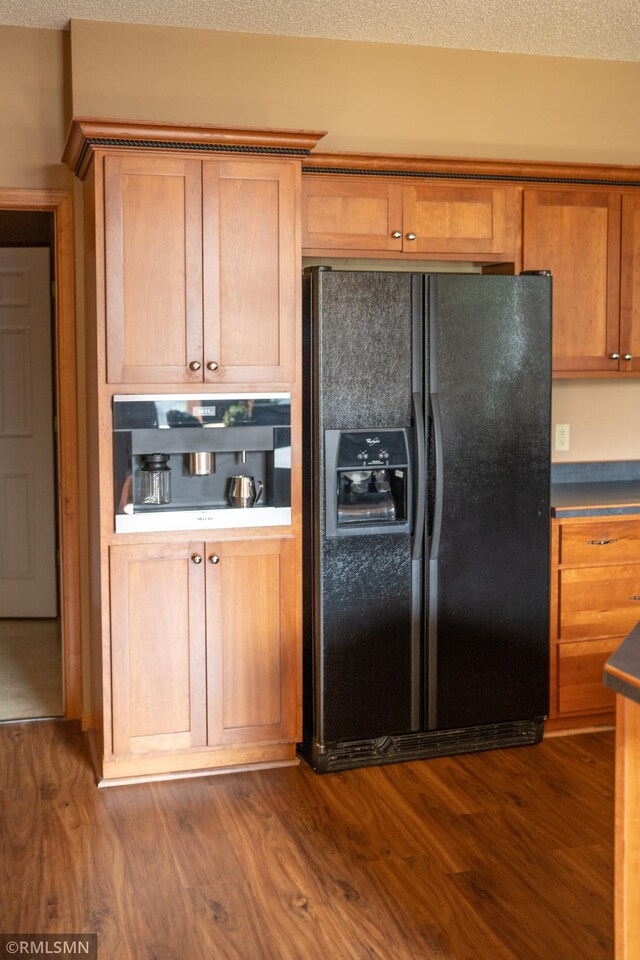 14578 Hunters Ln, Savage, MN 55378 - kitchen with black fridge with ice dispenser, dark wood-style flooring, brown cabinetry, and dark countertops