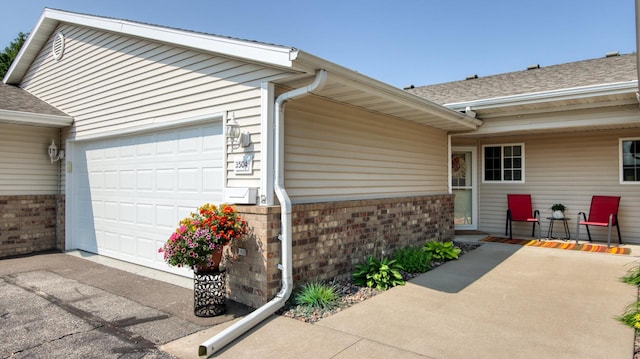 3504 Damon St Unit 38, Eau Claire, WI 54701 - property entrance featuring a garage, a shingled roof, brick siding, and asphalt driveway