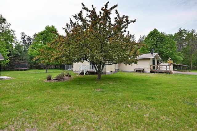 14102 Eau Claire Acres Cir, Gordon, WI 54838 - view of grassy yard with a trampoline and a wooden deck