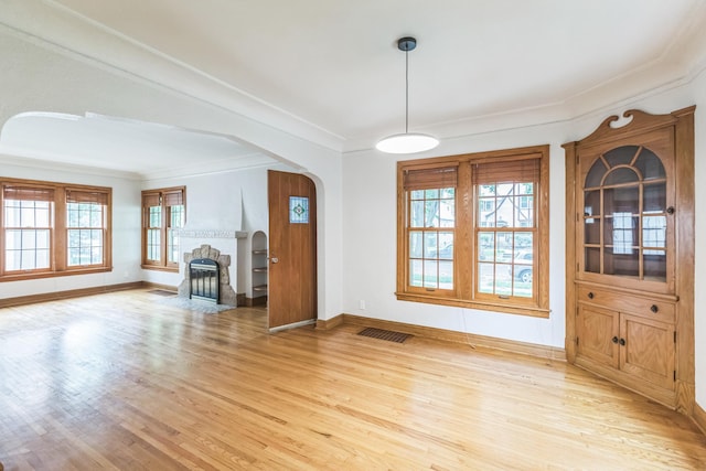 5223 15th Ave S, Minneapolis, MN 55417 - unfurnished living room featuring light wood-style flooring, crown molding, arched walkways, and a fireplace
