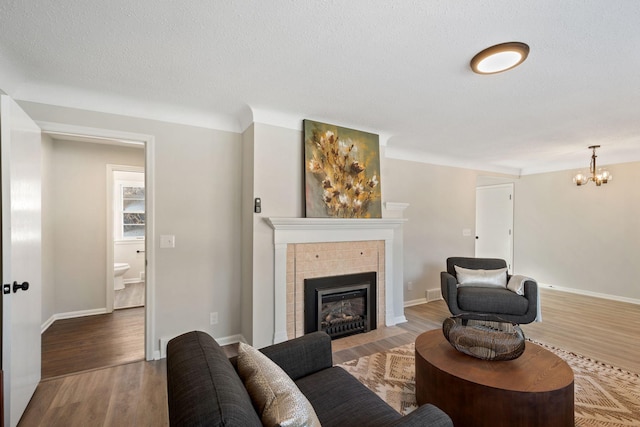 401 Plymouth Rd, Minnetonka, MN 55305 - living area featuring wood finished floors, a chandelier, a tiled fireplace, and a textured ceiling