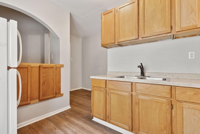 3208 Pleasant Ave, Minneapolis, MN 55408 - kitchen featuring light wood-style flooring, light countertops, light brown cabinetry, and freestanding refrigerator