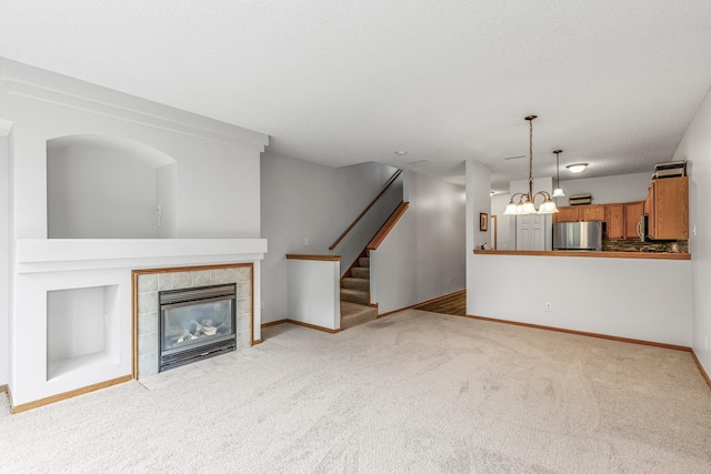 1587 Liberty St, Shakopee, MN 55379 - unfurnished living room featuring carpet floors, a tile fireplace, stairway, and a chandelier