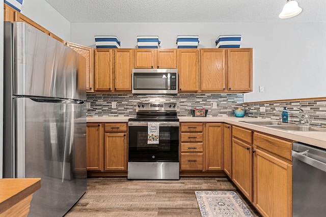 1587 Liberty St, Shakopee, MN 55379 - kitchen with stainless steel appliances, light countertops, a textured ceiling, backsplash, and light wood finished floors
