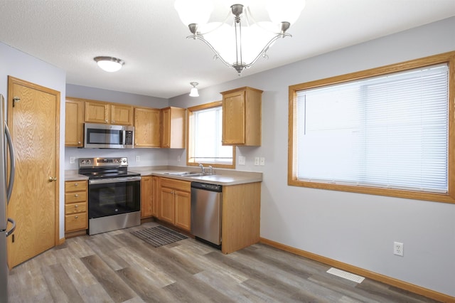 304 Tanager Path, Mankato, MN 56001 - kitchen with stainless steel appliances, a chandelier, light wood-style flooring, and light countertops
