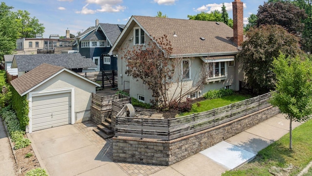 720 40th St, Minneapolis, MN 55409 - view of front of house featuring a chimney, concrete driveway, a shingled roof, stucco siding, and a residential view