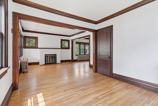 720 40th St, Minneapolis, MN 55409 - unfurnished living room featuring radiator, light wood-type flooring, crown molding, and a fireplace