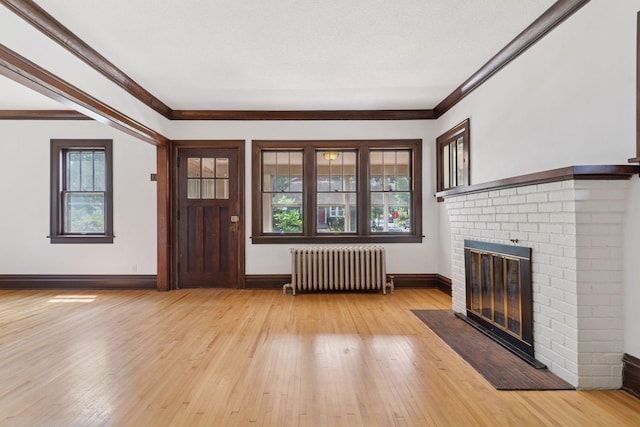 720 40th St, Minneapolis, MN 55409 - unfurnished living room with radiator heating unit, plenty of natural light, a brick fireplace, light wood finished floors, and crown molding