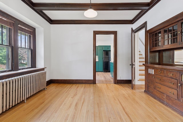 720 40th St, Minneapolis, MN 55409 - empty room with radiator heating unit, light wood-type flooring, stairs, ornamental molding, and beam ceiling