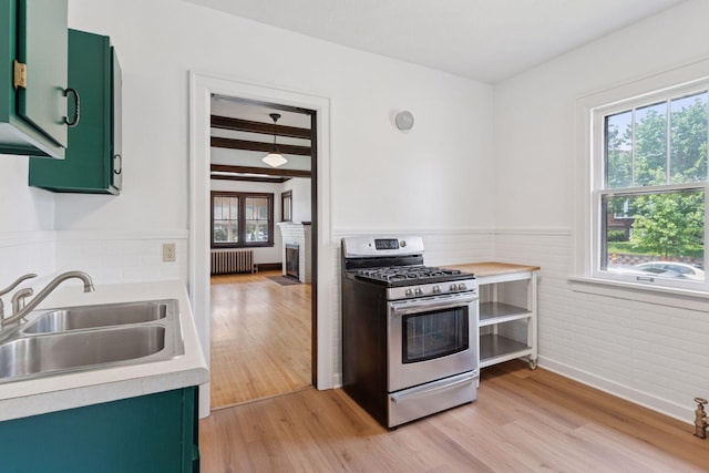 720 40th St, Minneapolis, MN 55409 - kitchen with green cabinets, stainless steel gas range oven, radiator, plenty of natural light, and wainscoting