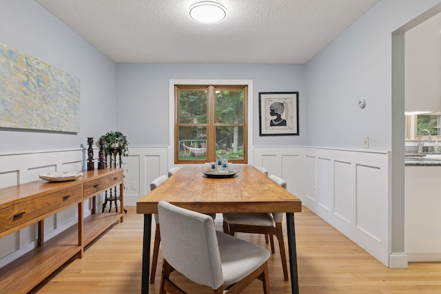 17233 Harrington Way, Lakeville, MN 55044 - dining area featuring a textured ceiling, light wood-type flooring, a wainscoted wall, healthy amount of natural light, and a decorative wall