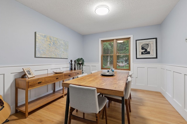 17233 Harrington Way, Lakeville, MN 55044 - dining room with a textured ceiling, a decorative wall, light wood-style flooring, and wainscoting
