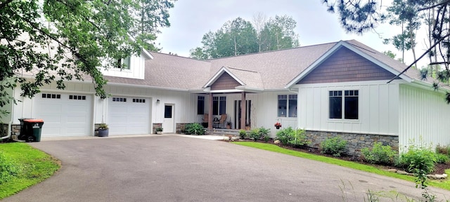 9029 Crown Hill Ct, Brainerd, MN 56401 - view of front of house featuring board and batten siding, asphalt driveway, stone siding, a porch, and an attached garage