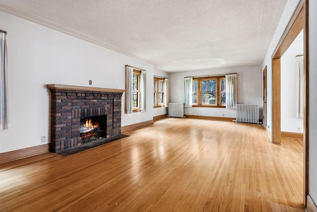 4300 Beard Ave S, Minneapolis, MN 55410 - unfurnished living room featuring radiator heating unit, light wood-style flooring, a fireplace, and a textured ceiling