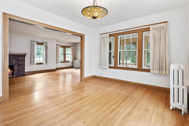 4300 Beard Ave S, Minneapolis, MN 55410 - empty room with radiator heating unit, light wood-style floors, radiator, a fireplace, and ornamental molding