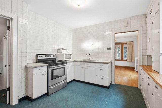 4300 Beard Ave S, Minneapolis, MN 55410 - kitchen with stainless steel range with electric stovetop, tile walls, white microwave, radiator, and white cabinets