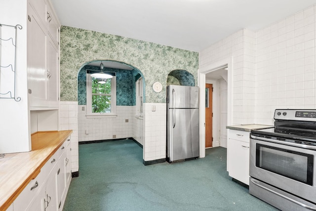 4300 Beard Ave S, Minneapolis, MN 55410 - kitchen with appliances with stainless steel finishes, tile walls, wallpapered walls, white cabinets, and dark carpet