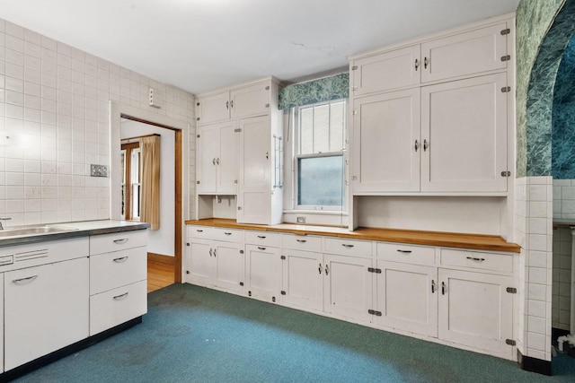 4300 Beard Ave S, Minneapolis, MN 55410 - kitchen with wooden counters, dark carpet, white cabinetry, and tile walls