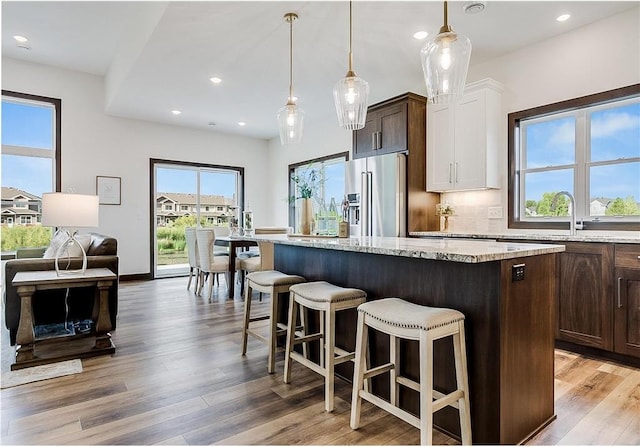 117 Maple Ct, Cannon Falls, MN 55009 - kitchen with high end refrigerator, a center island, a kitchen breakfast bar, light stone counters, and recessed lighting
