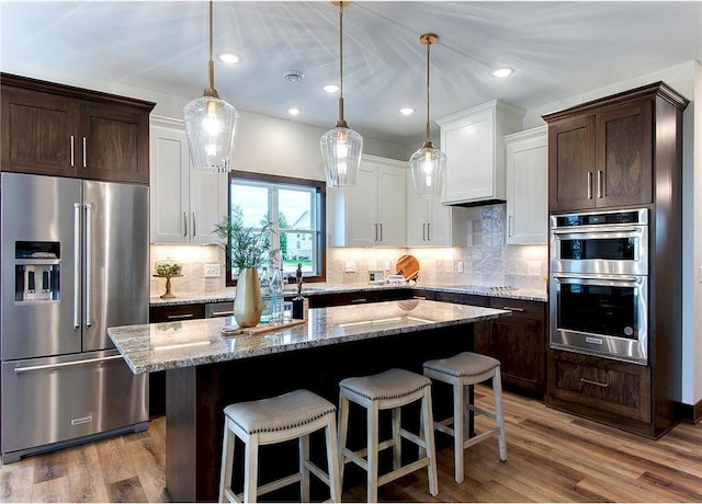 117 Maple Ct, Cannon Falls, MN 55009 - kitchen featuring appliances with stainless steel finishes, dark brown cabinetry, white cabinetry, a kitchen island, and recessed lighting