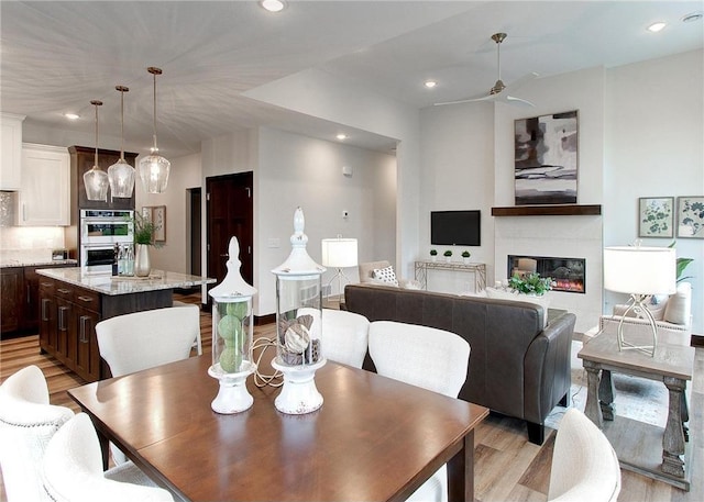 117 Maple Ct, Cannon Falls, MN 55009 - dining room with light wood finished floors, a ceiling fan, recessed lighting, and a glass covered fireplace