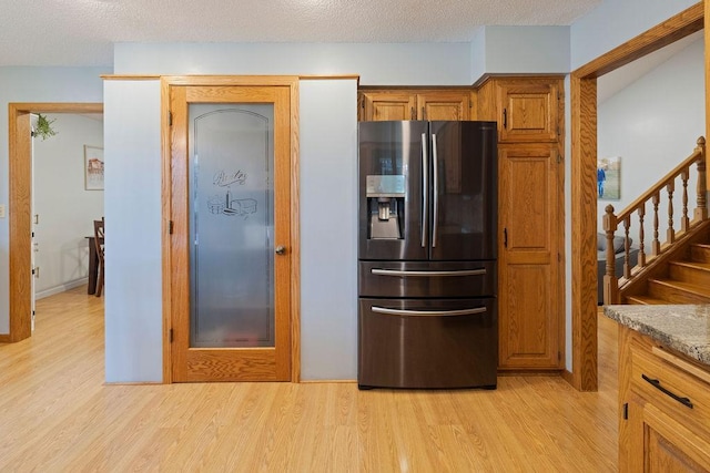 1008 3rd St NE, New Prague, MN 56071 - kitchen featuring stainless steel fridge, light wood-style floors, brown cabinets, and a textured ceiling