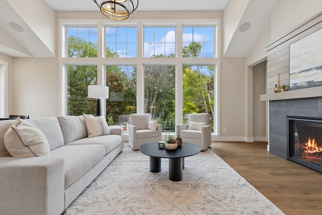 2706 Lakeview Ct, Little Canada, MN 55117 - living area featuring a fireplace, a chandelier, wood finished floors, and a towering ceiling
