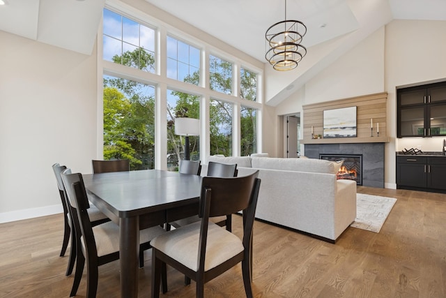 2706 Lakeview Ct, Little Canada, MN 55117 - dining area with high vaulted ceiling, a chandelier, a tiled fireplace, and light wood-style flooring