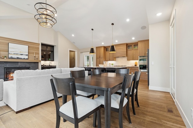 2706 Lakeview Ct, Little Canada, MN 55117 - dining area with light wood-type flooring, a glass covered fireplace, recessed lighting, and high vaulted ceiling