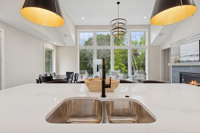 2706 Lakeview Ct, Little Canada, MN 55117 - kitchen featuring open floor plan, a high ceiling, a fireplace, light stone counters, and pendant lighting