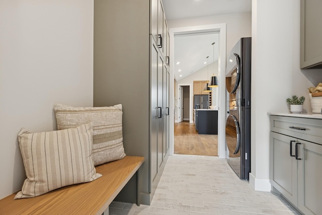 2706 Lakeview Ct, Little Canada, MN 55117 - hallway with stacked washing machine and dryer, light wood-style flooring, lofted ceiling, and recessed lighting