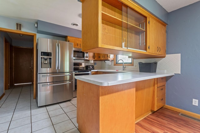 39743 County Road 1, Brockway Twp, MN 56367 - kitchen featuring appliances with stainless steel finishes, a peninsula, light countertops, backsplash, and light tile patterned floors