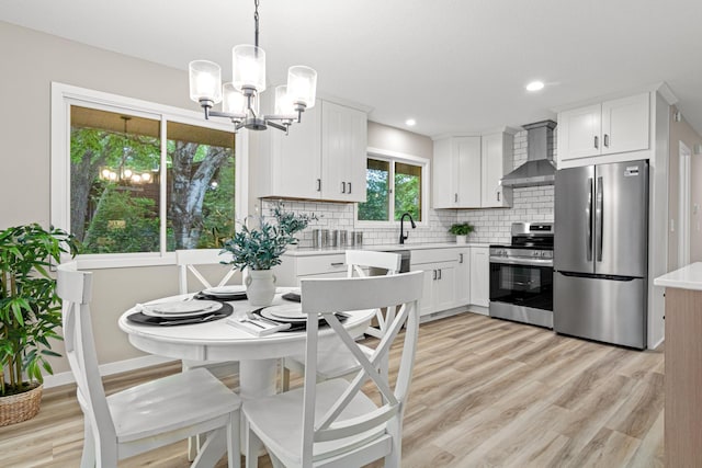 6980 Crest Dr, Maple Grove, MN 55311 - kitchen with appliances with stainless steel finishes, wall chimney exhaust hood, a chandelier, light countertops, and tasteful backsplash