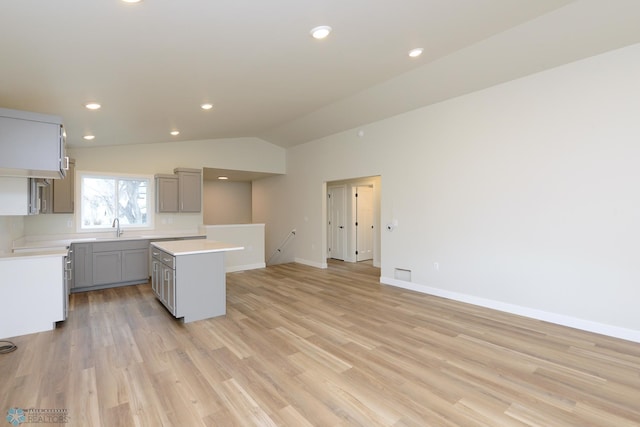 1109 University Dr S, Fargo, ND 58103 - kitchen with gray cabinets, a kitchen island, light countertops, light wood-style floors, and lofted ceiling