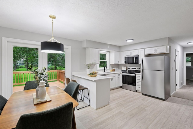 711 9th St NW, Buffalo, MN 55313 - kitchen with appliances with stainless steel finishes, healthy amount of natural light, a peninsula, light countertops, and a textured ceiling