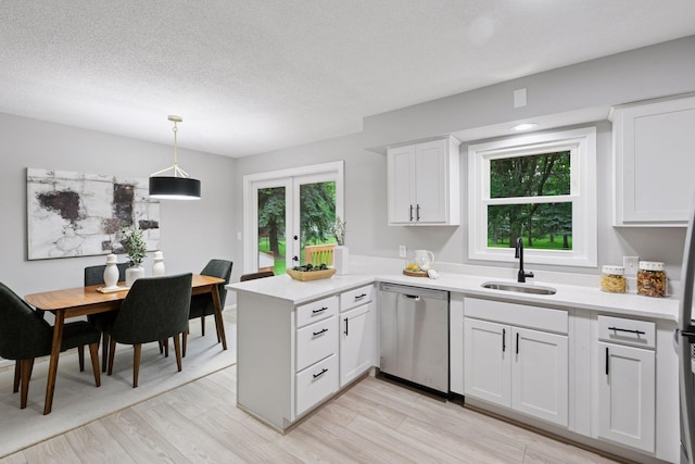711 9th St NW, Buffalo, MN 55313 - kitchen with dishwasher, a peninsula, light wood-style flooring, light countertops, and a textured ceiling