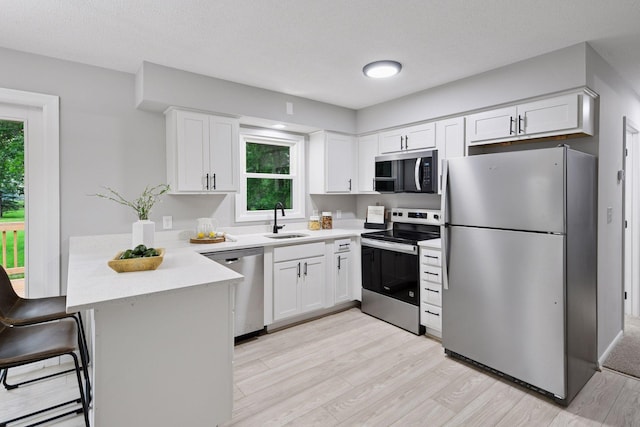 711 9th St NW, Buffalo, MN 55313 - kitchen with appliances with stainless steel finishes, a peninsula, light wood-style flooring, and healthy amount of natural light