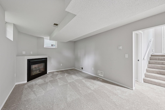 711 9th St NW, Buffalo, MN 55313 - basement with carpet floors, stairway, a glass covered fireplace, and a textured ceiling