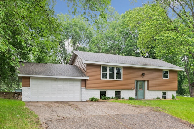 711 9th St NW, Buffalo, MN 55313 - raised ranch featuring a front yard, asphalt driveway, a garage, and a shingled roof
